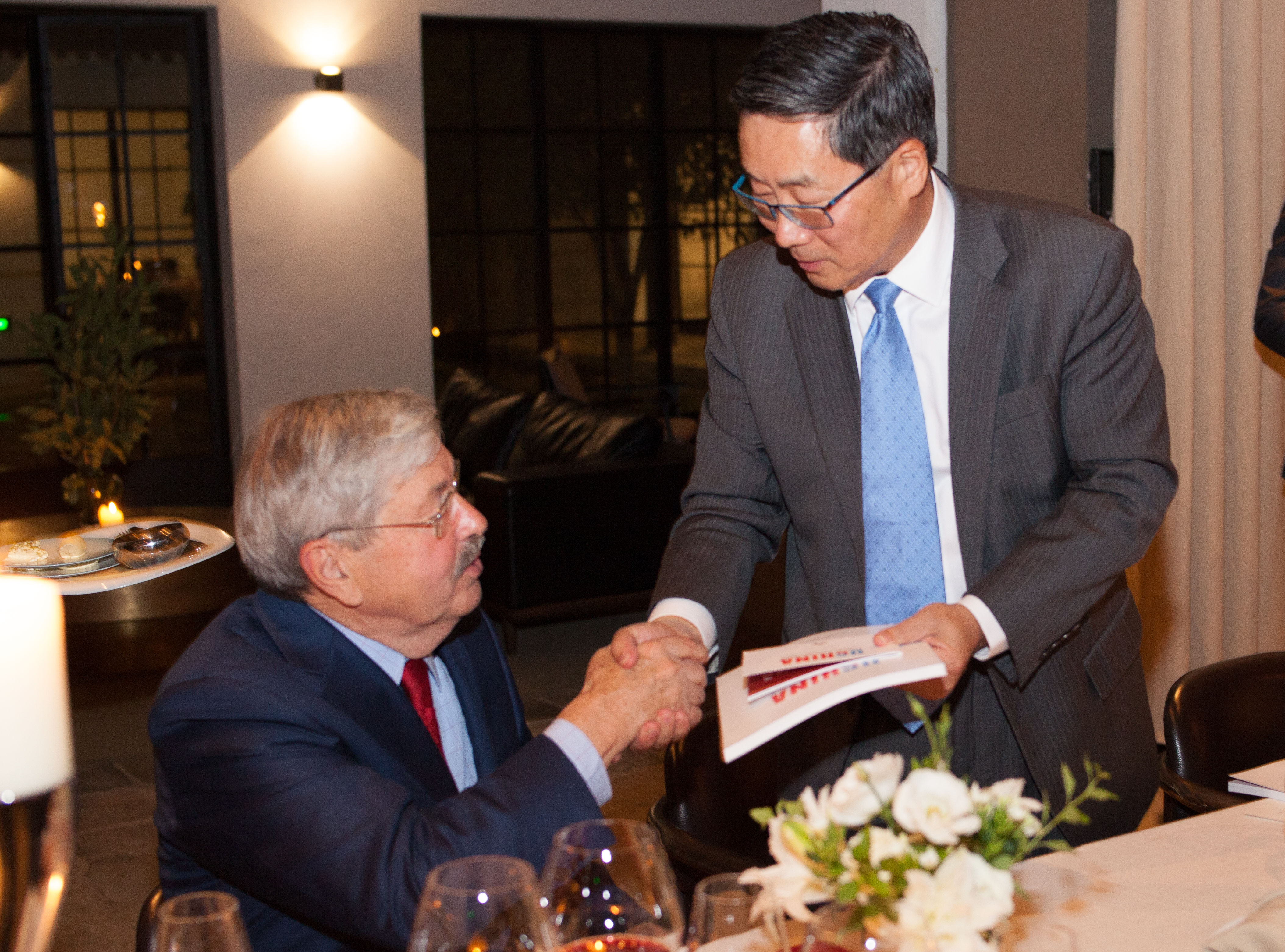 Dazong Wang and Ambassador Branstad shaking hands, giving survey